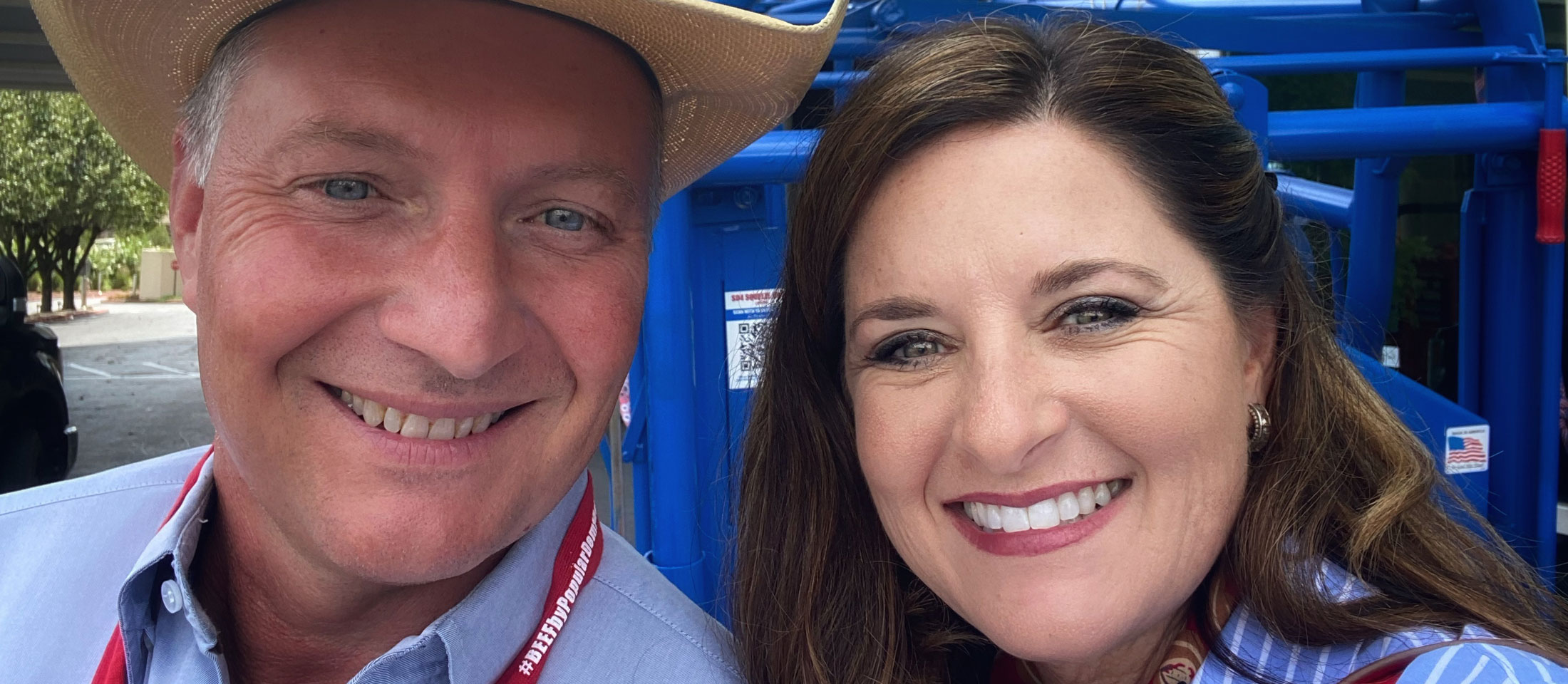 Roger and Nikki Callison of Callison Ranch beef wearing blue shirts and posing in front of a blue fence.